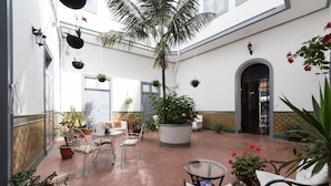 A courtyard with a palm tree, potted plants, and outdoor seating. - Casa Cinzia (Las Palmas de Gran Canaria)
