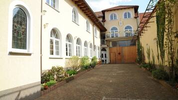 Un patio con un sendero adoquinado, ventanas de arco y una puerta de madera.