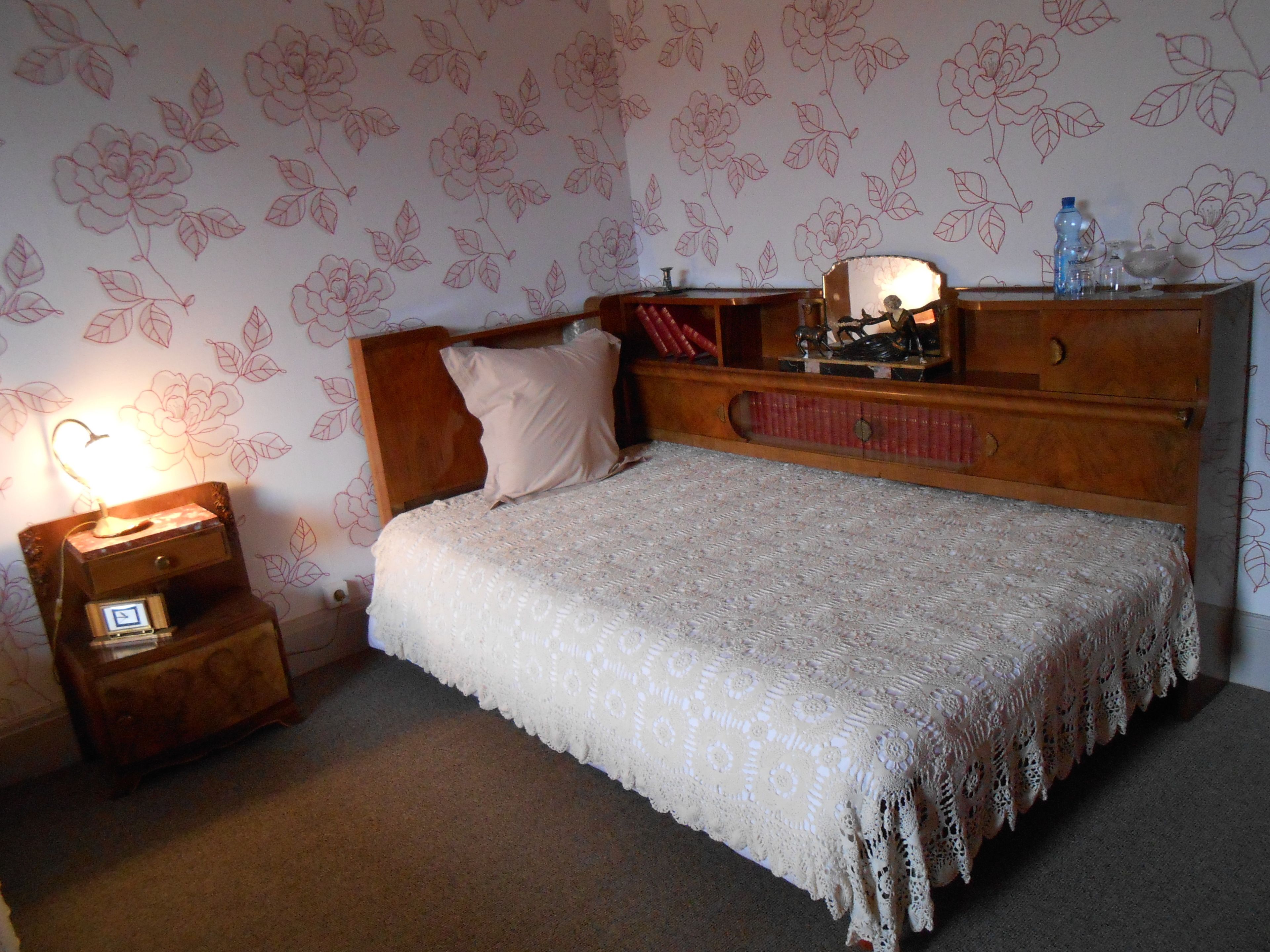 Une chambre à coucher avec un lit en bois, une table de chevet avec une lampe et une commode avec un miroir.