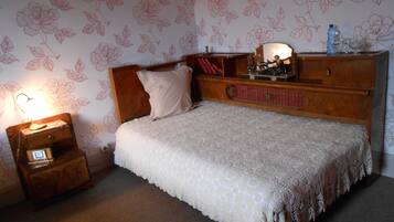 Una camera da letto con un letto in legno, un comodino con una lampada e una cassettiera con uno specchio.