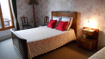 A neatly made bed with a white and red patterned bedspread, a wooden headboard, and a bedside table with a lamp.