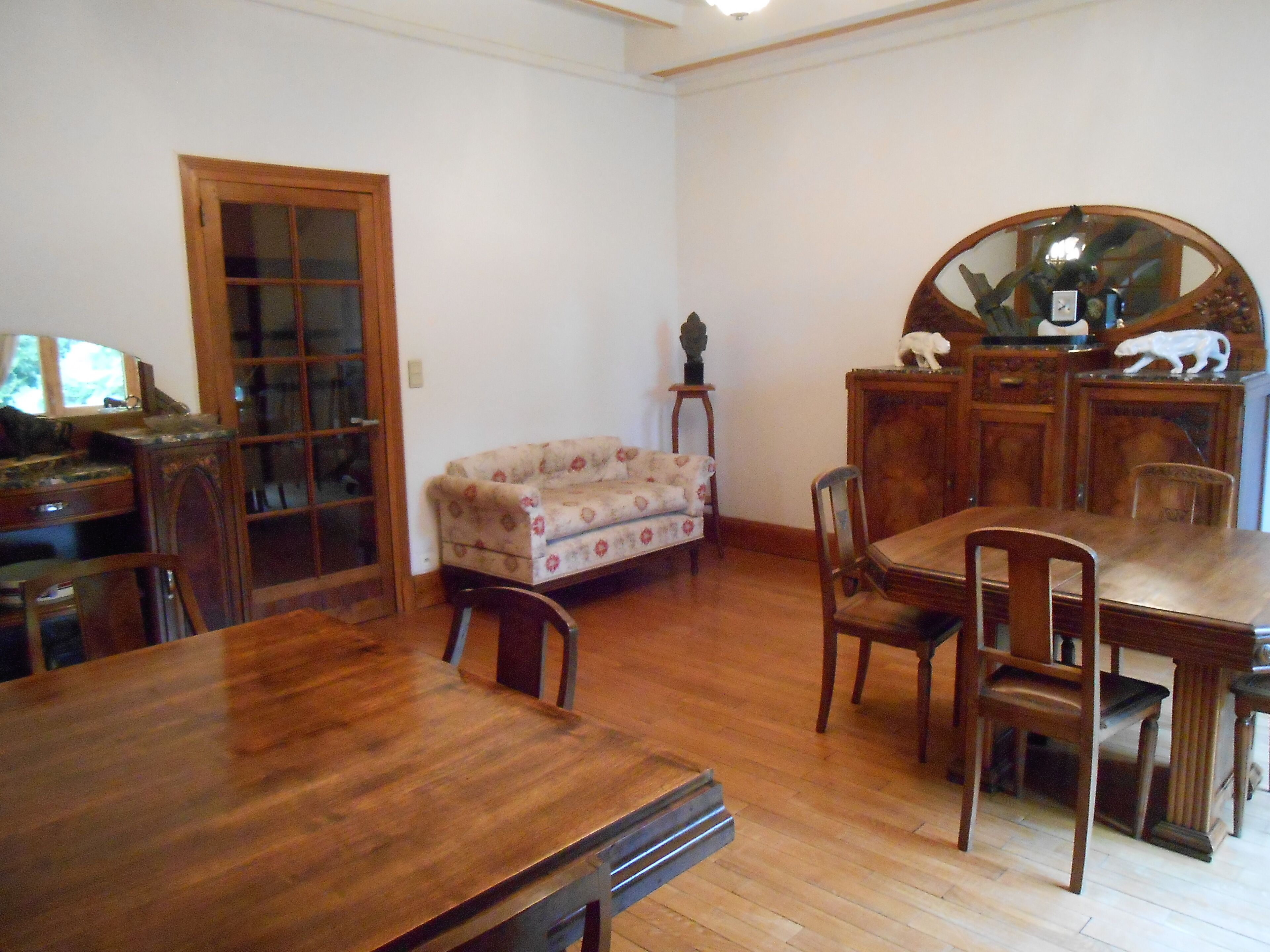 Un comedor con una mesa y sillas de madera, un sofá, un aparador de madera y un espejo.