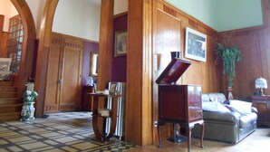 A spacious room with high wooden arches, a piano, a sofa, and a staircase. - La Passagère (Hauterive)