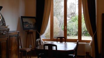 A dining room with a wooden table and chairs, a radiator, and a painting on the wall.