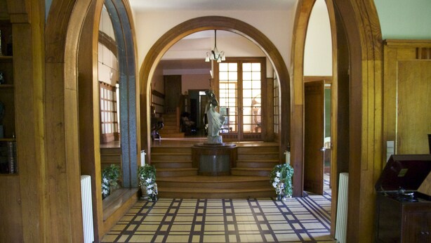A hallway with wooden arches, a patterned floor, and a statue in the center. - La Passagère (Hauterive)