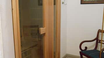 Una puerta de madera con un panel de vidrio, una silla y un cuadro en la pared.