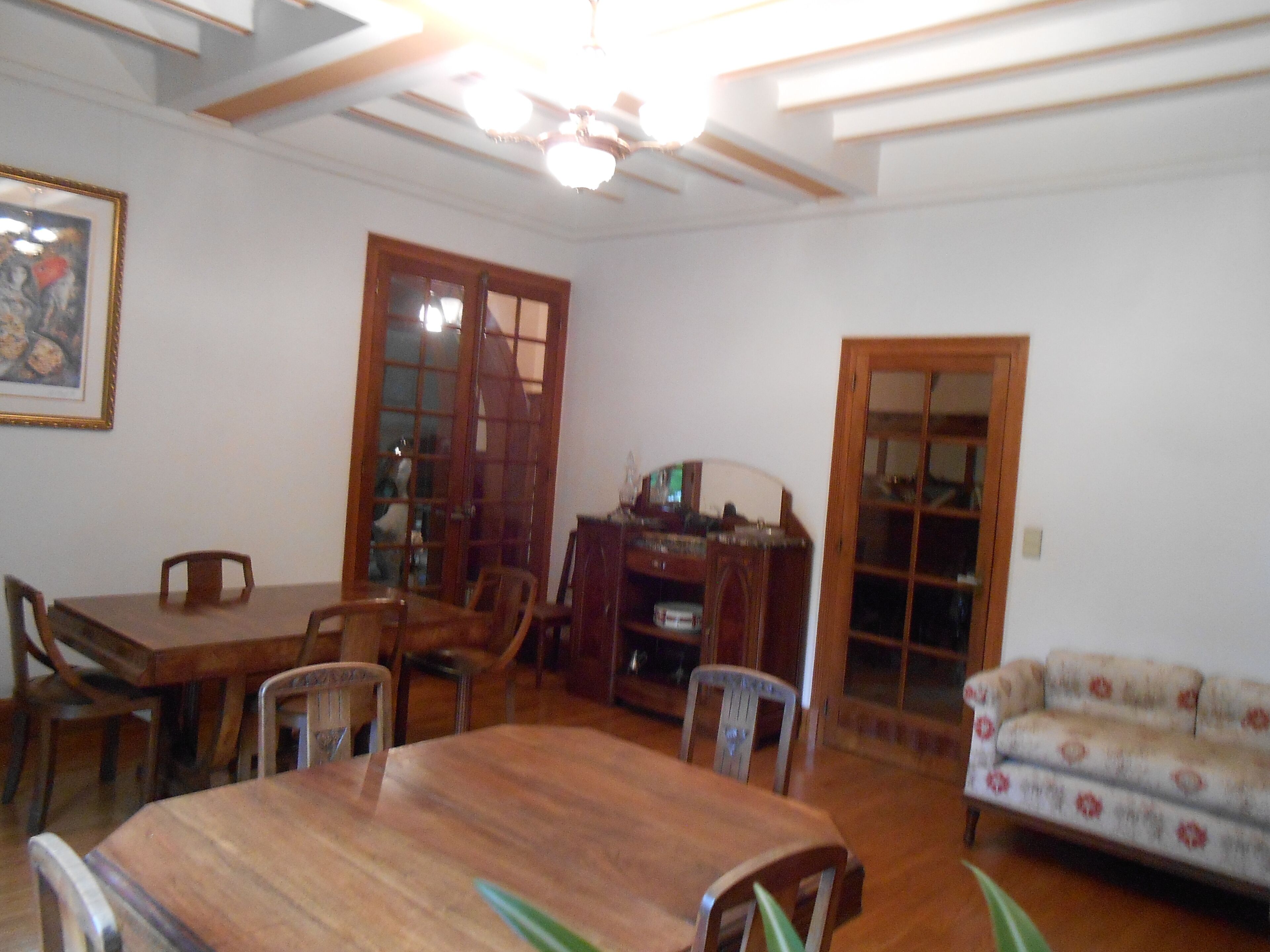 A dining area with a wooden table and chairs, a sofa, and a cabinet.