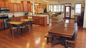 A spacious kitchen with wooden cabinets, a large island, and a dining area with a long table and chairs.