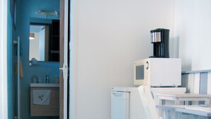 Una kitchenette compacta equipada con microondas, cafetera y un refrigerador pequeño.