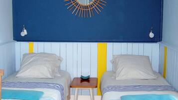 A room with two beds, a small table, and a wall-mounted mirror.
