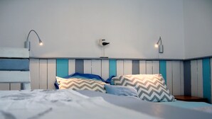 Una cama con almohadillas estampadas, un cabecero de madera y luces fijadas a la pared.