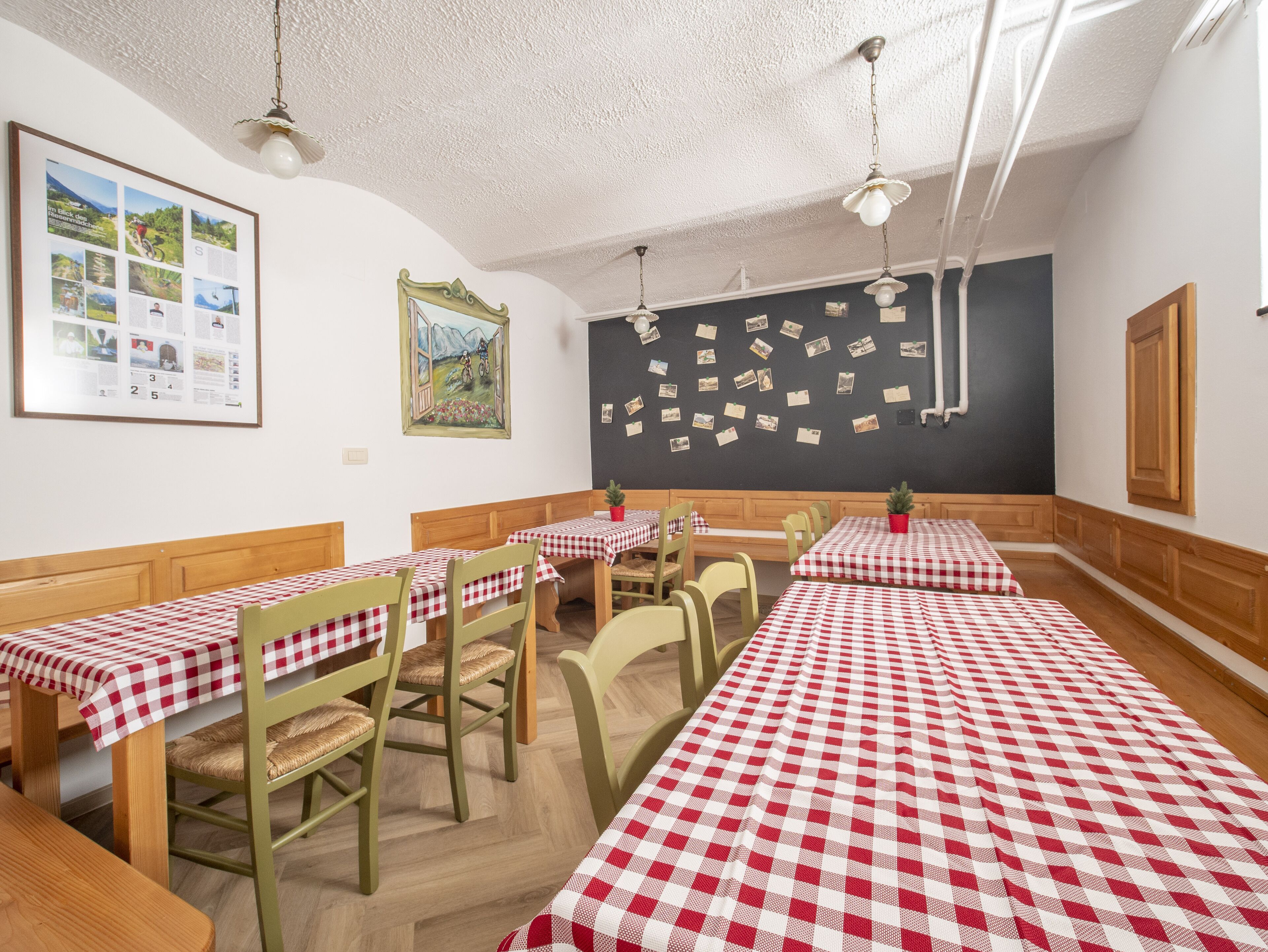 A dining area with checkered tablecloths, wooden benches, and chairs.