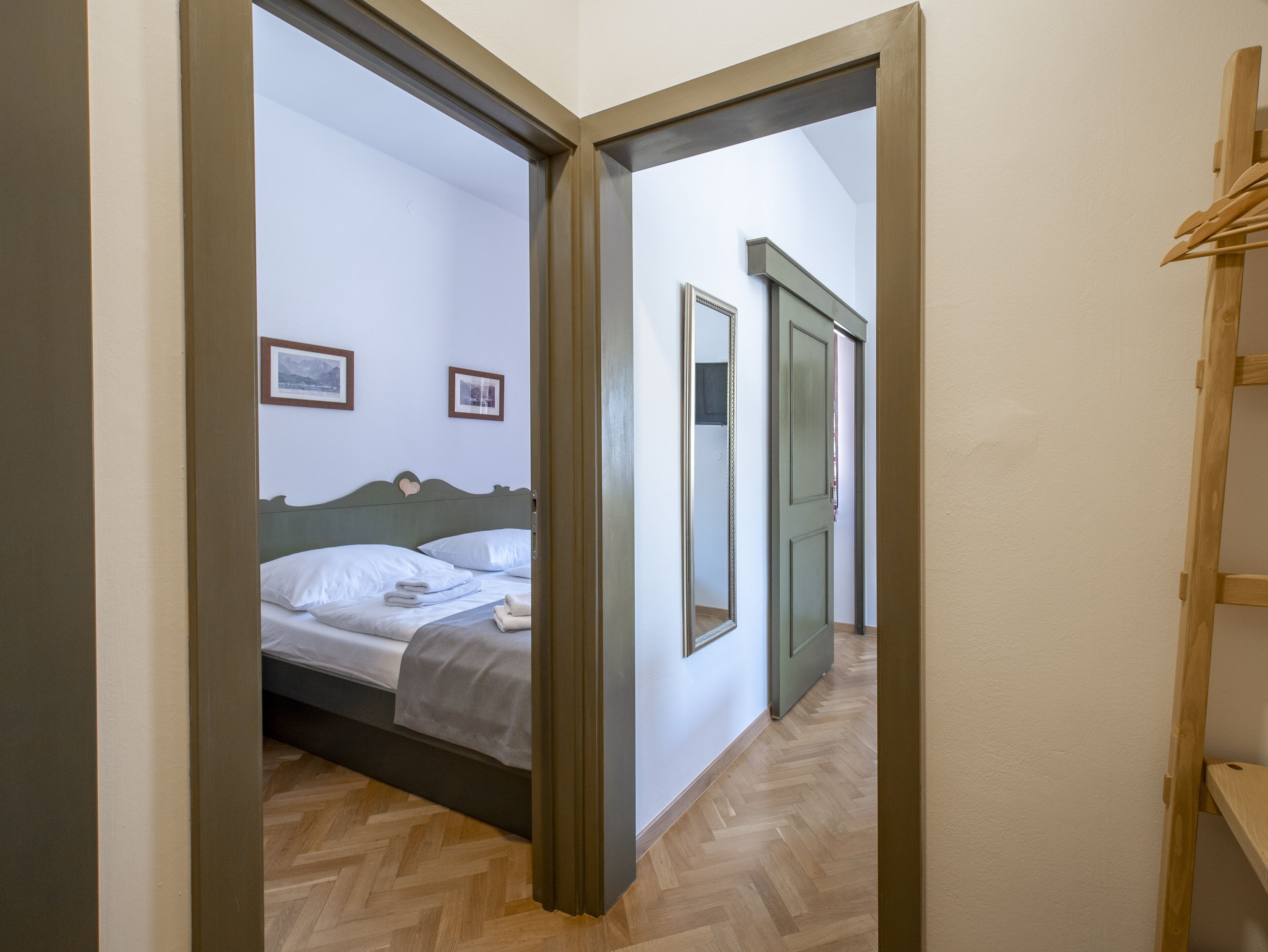 Un dormitorio con cama, piso de madera y puerta que da a otra habitación.