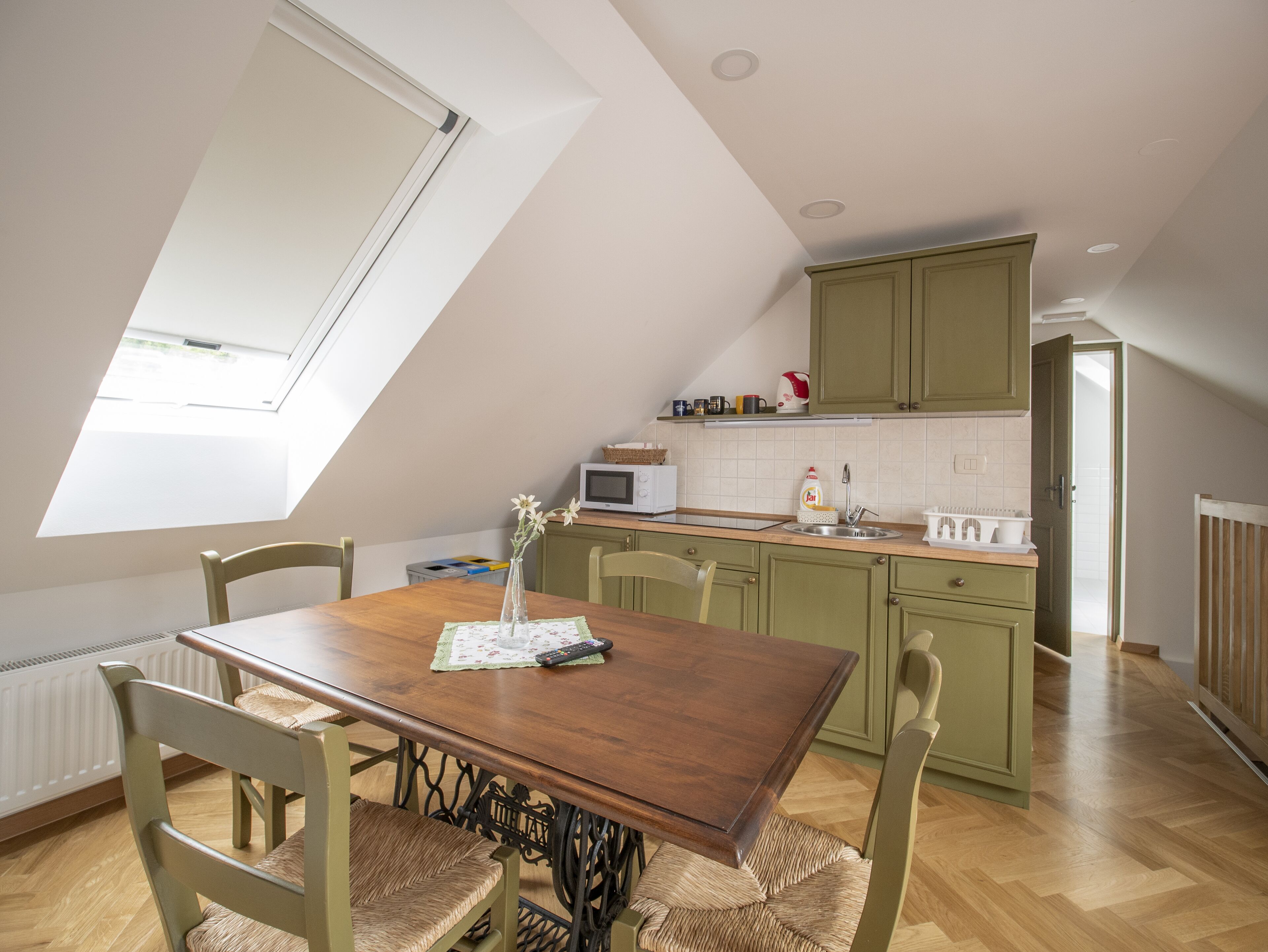 Un comedor con mesa y sillas de madera, una ventana con vistas y una cocina al fondo.