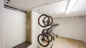Una habitación con una puerta blanca, un banco y un perchero para bicicletas fijado a la pared, con dos bicicletas.