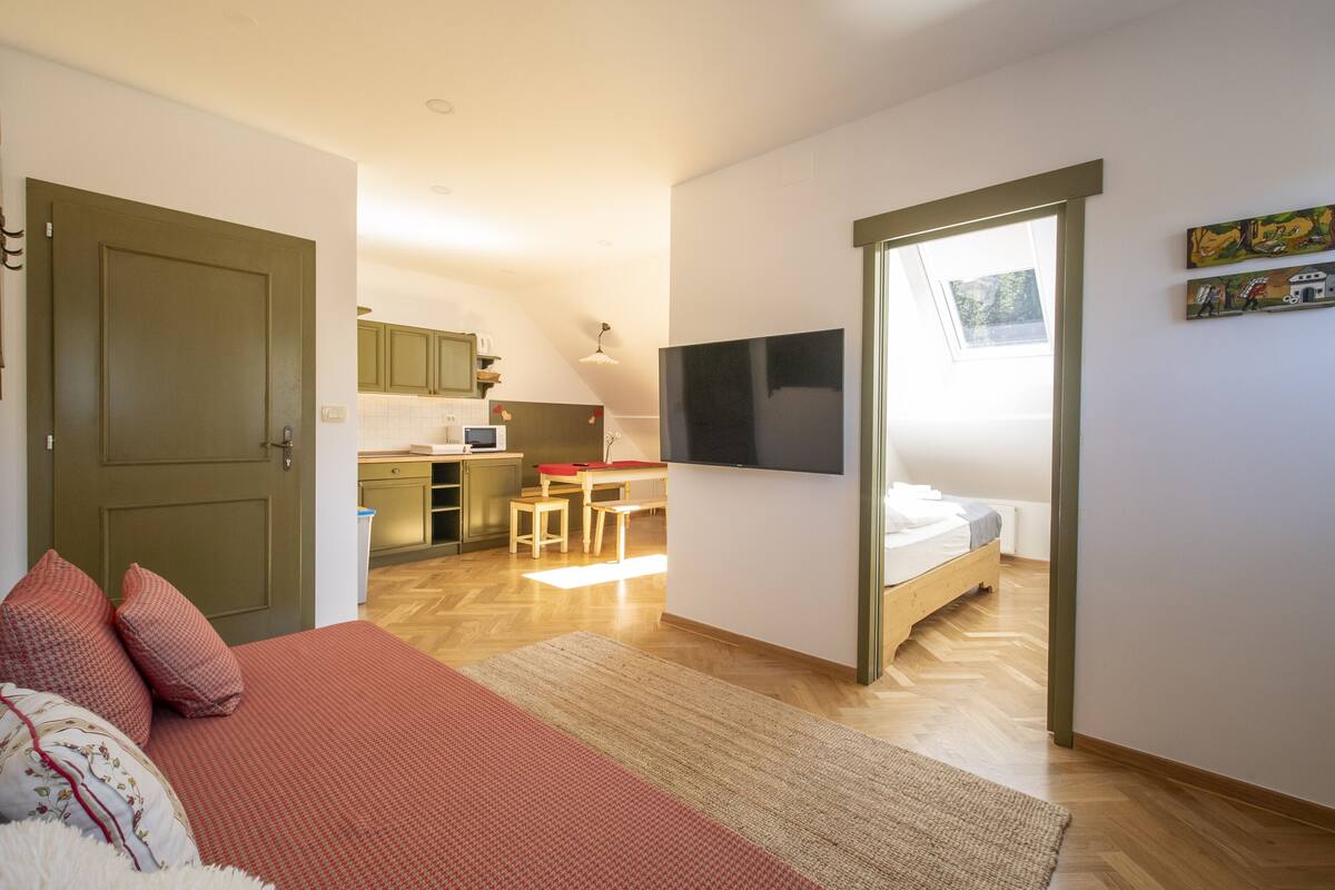 Un dormitorio con cama, televisor y vista a la cocina.