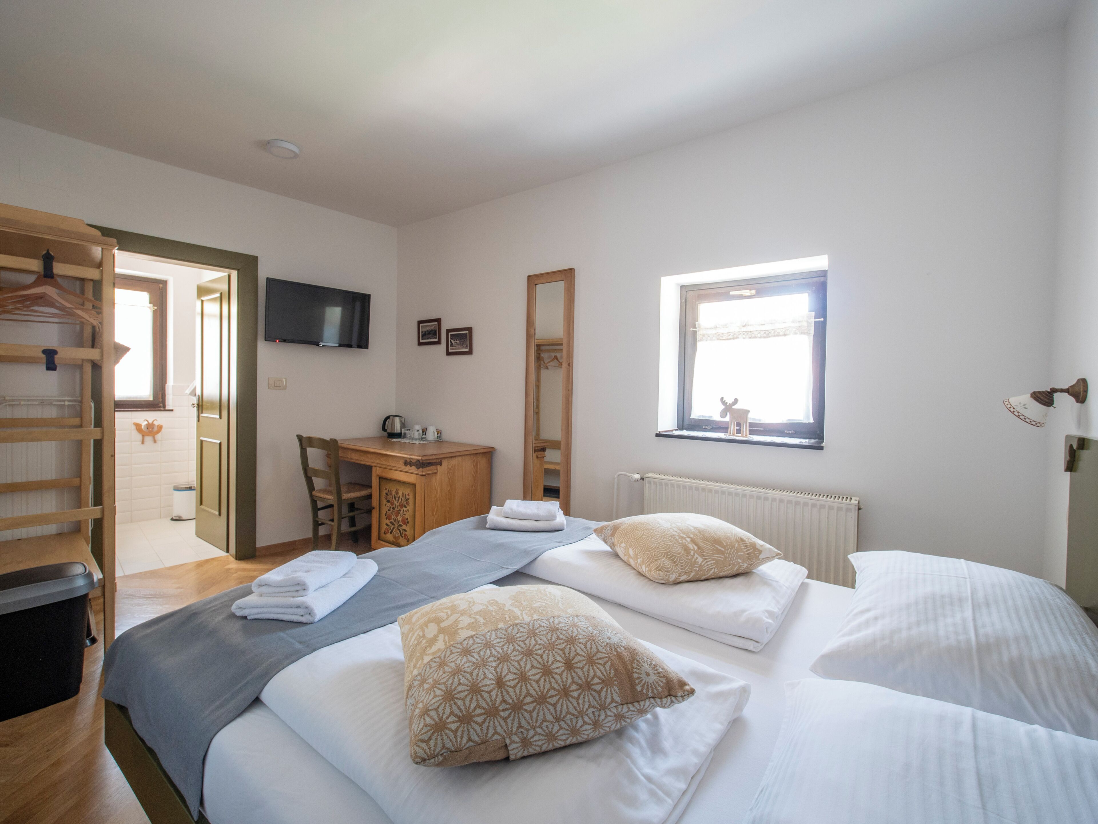 Hotelkamer met twee bedden, een bureau, een stoel, een televisie en een raam met uitzicht op een hert.