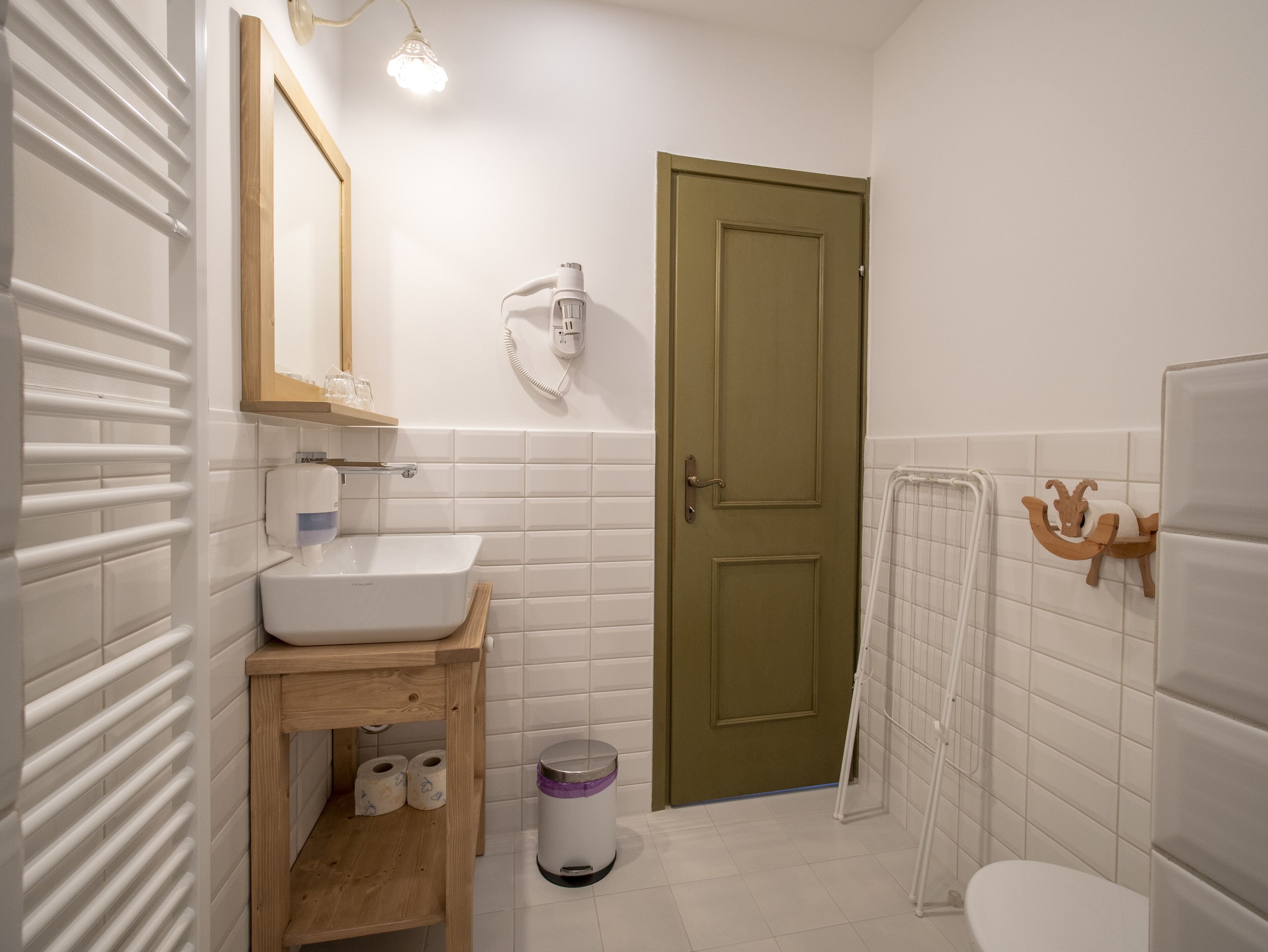 A bathroom with a white sink, wooden vanity, toilet, and a green door.
