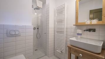A modern bathroom with a shower, toilet, and sink.
