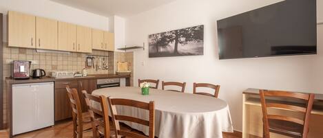 Cocina compacta con armarios de madera, horno empotrado y comedor con mesa y sillas redondas.