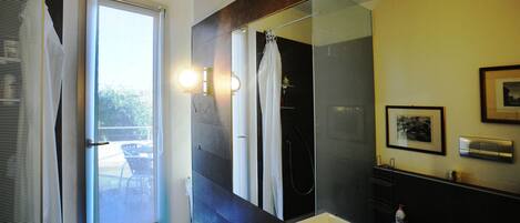 A bathroom with a large mirror, a sink, and a shower.
