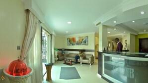 A hotel lobby with a reception desk, a sofa, a coffee table, and a decorative red sphere. - Celia's Suites (Abeokuta)