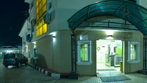 A hotel entrance with a covered entrance, a reception desk, and a car parked in front. - Celia's Suites (Abeokuta)