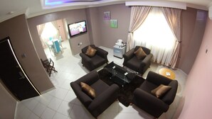 A modern living room with a sofa set, a coffee table, and a TV mounted on the wall. - Celia's Suites (Abeokuta)