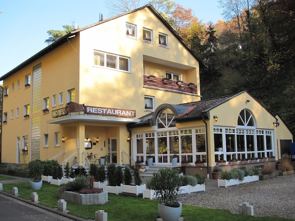 A yellow building with a sign indicating it is a hotel and restaurant.