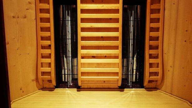 Una sala de sauna con paredes de madera, un banco y dos ventanas pequeñas.