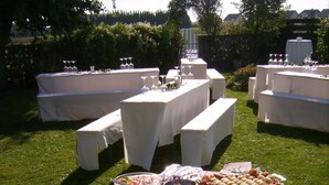 Un bufé al aire libre con diversos alimentos y bebidas sobre mesas.