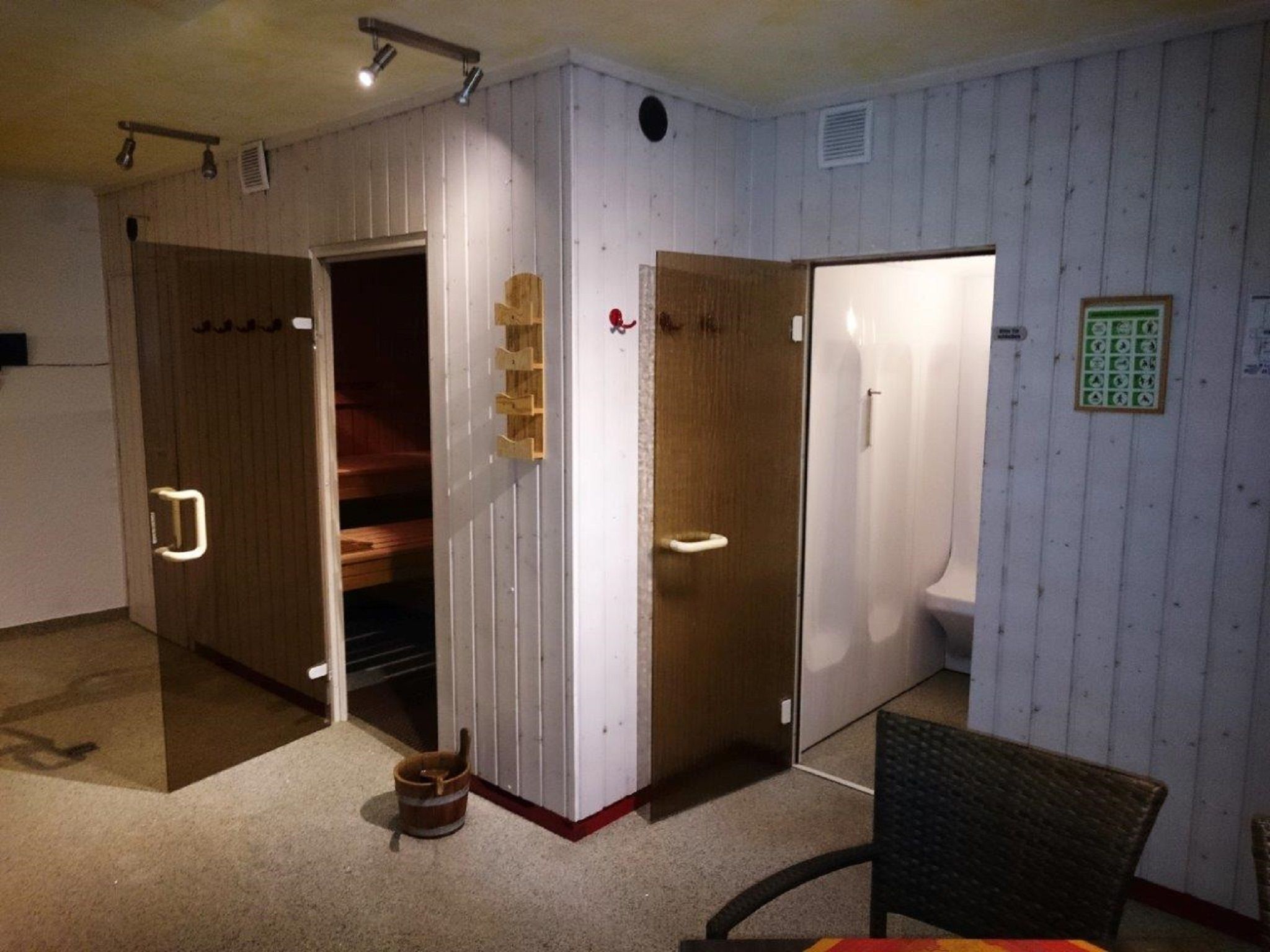 Ein Raum mit drei Holzt üren, jede Tür führt zu einer separaten Toilette. Auf dem Boden steht ein kleiner Holzeimer.