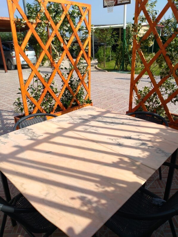 A table with a marble top, surrounded by a lattice structure with plants.