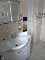A bathroom with a white sink, a mirror, and a towel dispenser.