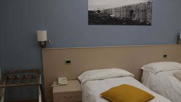 Habitación de hotel con dos camas, una mesita de noche con teléfono, una lámpara de pared y un cuadro en la pared.