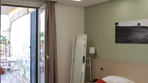 Une chambre d’hôtel avec un lit, une table de chevet, un miroir et une vue sur le balcon extérieur.