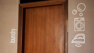 A wooden door with a laundry symbol and a washing machine symbol on the wall.
