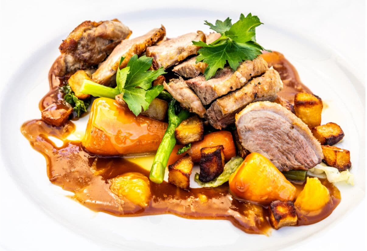 Un piatto con carne, patate e verdure.