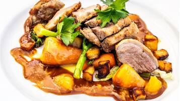 Un piatto con carne, patate e verdure.