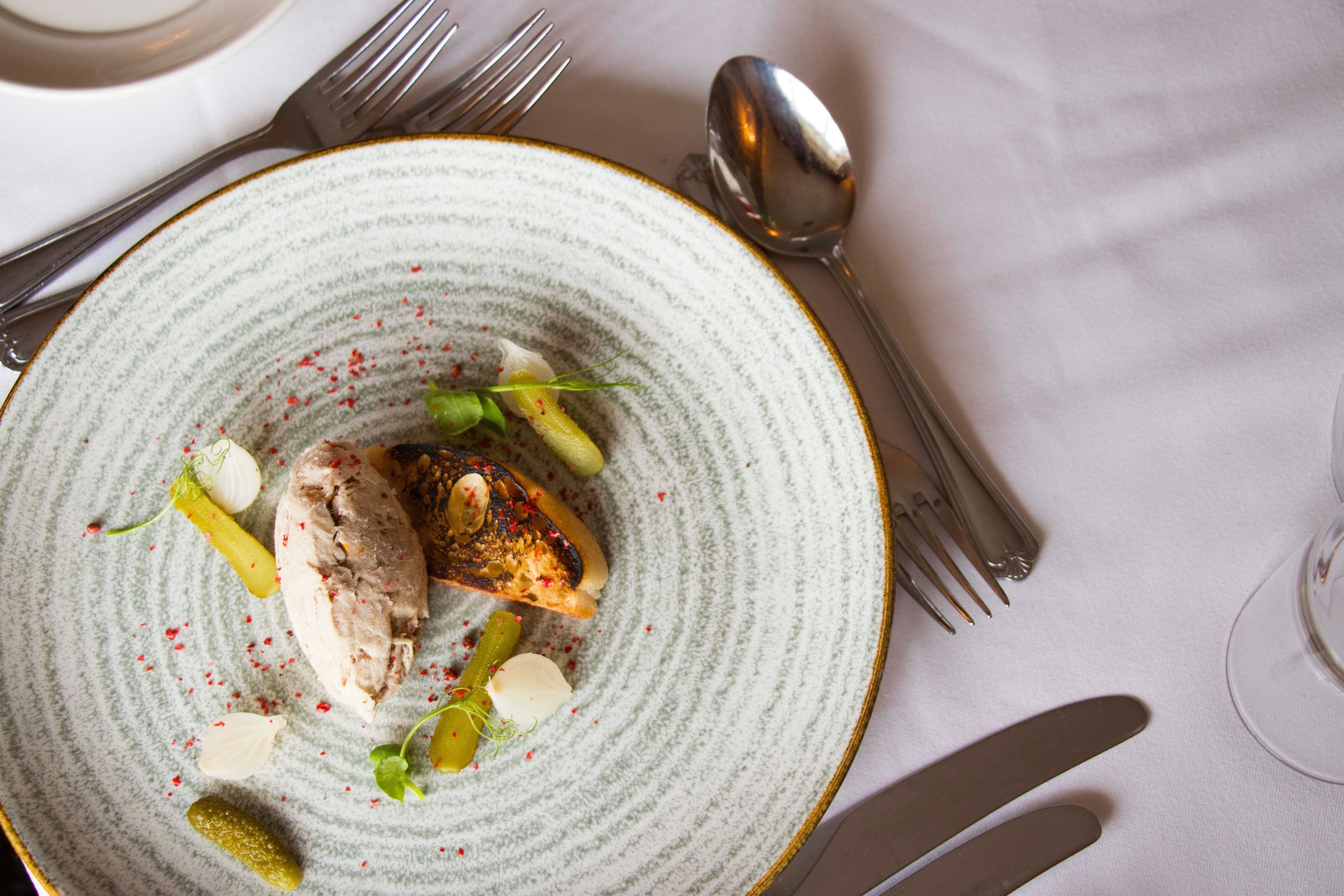 A plate of food with a fork and spoon on the table.