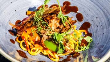 A dish with various vegetables and meat, served on a ceramic plate.