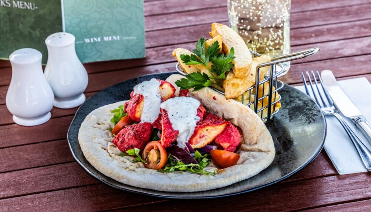 Ein Teller Essen mit Salat, Fleisch und Brot auf einer Holztisch.
