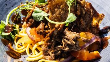 A dish with shredded meat, vegetables, and pasta on a plate.