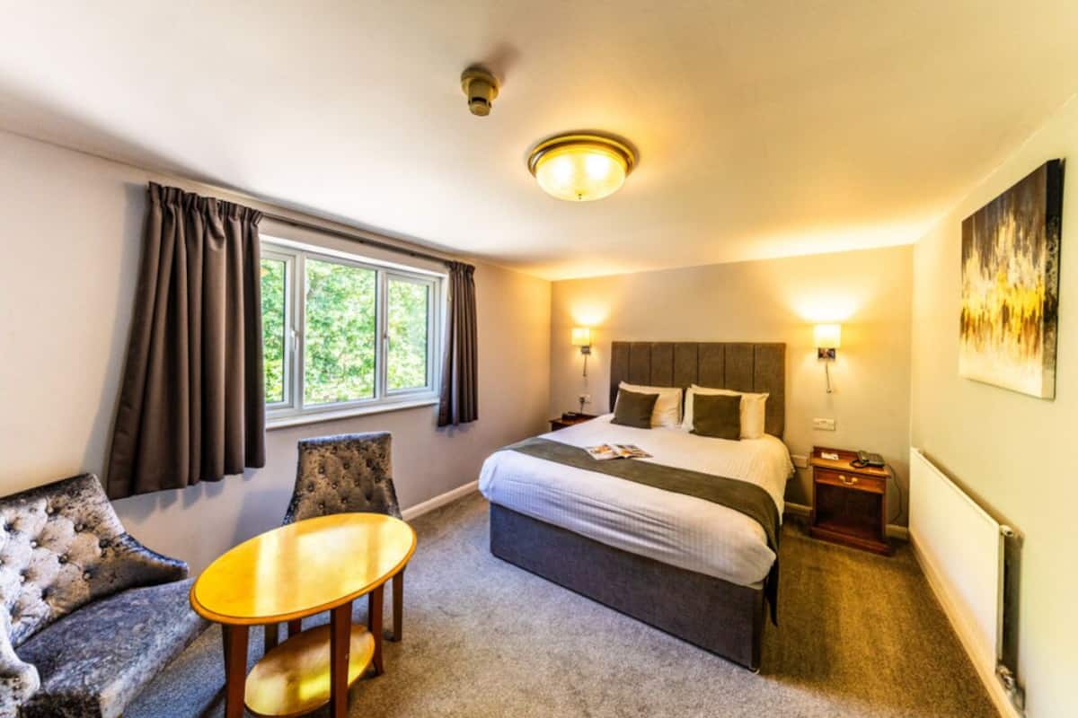 Ein Hotelzimmer mit einem Bett, einem kleinen Tisch, einer Couch und einem Fenster mit Vorhängen.