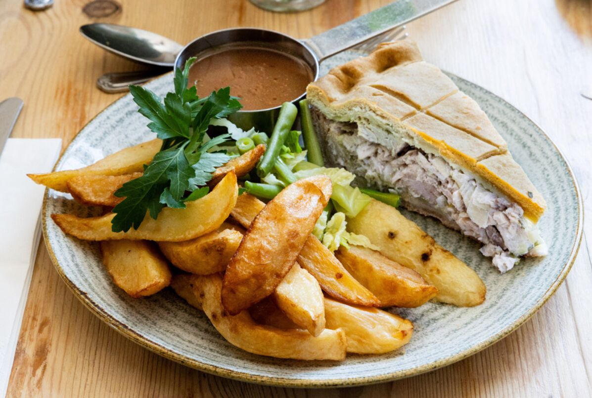 Une assiette avec un sandwich, des frites et un petit bol de sauce.