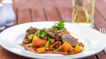 Prato de comida com carne e legumes sobre uma mesa de madeira.
