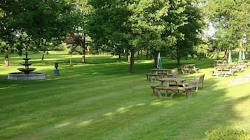 A park with a fountain, picnic tables, and umbrellas.