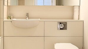 A modern bathroom with a white sink, mirror, and toilet. - Still Life St. Paul's Executive (London)