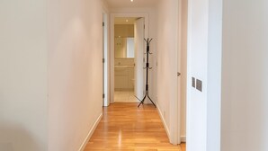 A hallway with wooden flooring leading to a bathroom with a toilet and sink. - Still Life St. Paul's Executive (London)