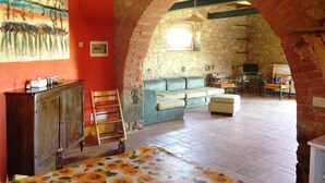 An interior with a stone archway, a sofa, a table, and a painting on the wall. - Agriturismo La Valentina Nuova (Orbetello)